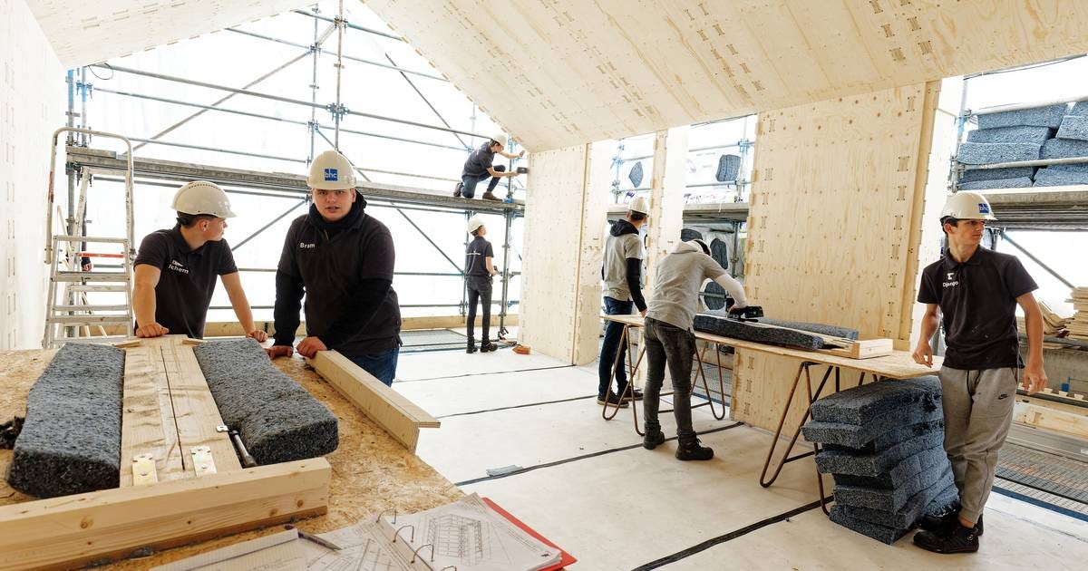 7 teenagers work with insulation material made from denim. They are working inside a WikiHouse structure which will be used as a classroom when finished 7 teenagers work with insulation material made from denim. They are working inside a WikiHouse structure which will be used as a classroom when finished