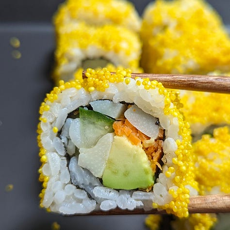 Three types of plant-based uramaki sushi rolls, each topped with colorful ingredients. The rolls have rice on the outside and are sliced into bite-sized pieces.