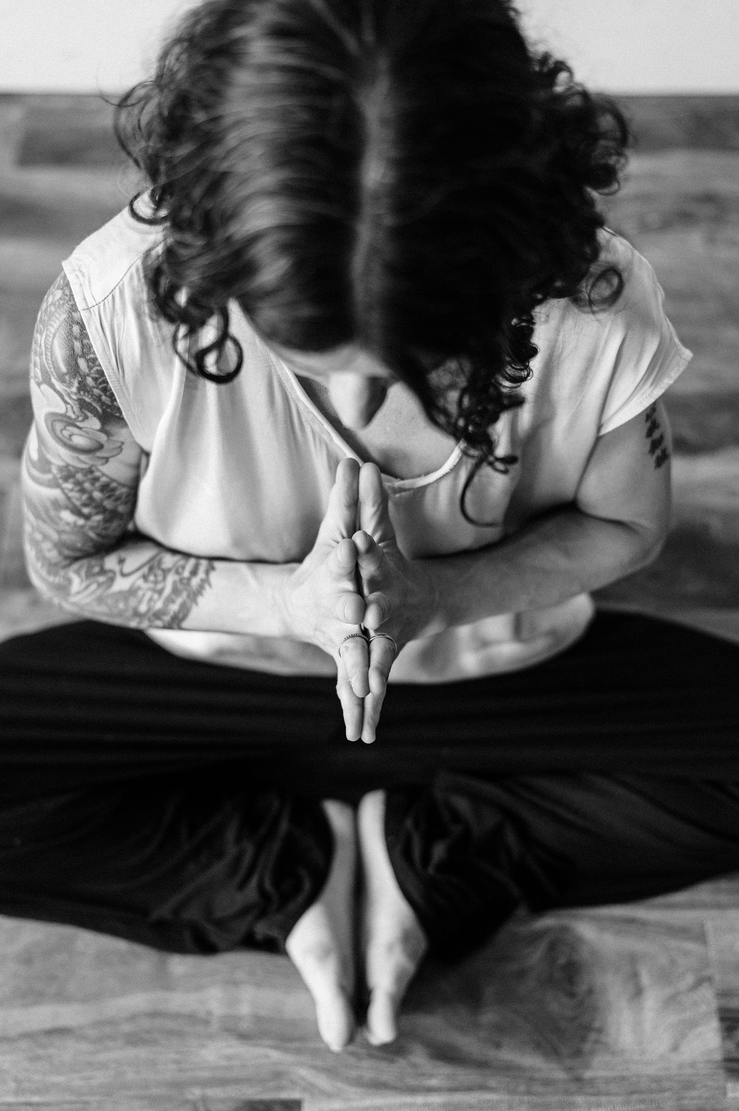 author seated and bowing with hands in prayer