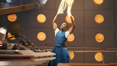 The Doctor reaches towards the ceiling while regeneration energy streams from their hands