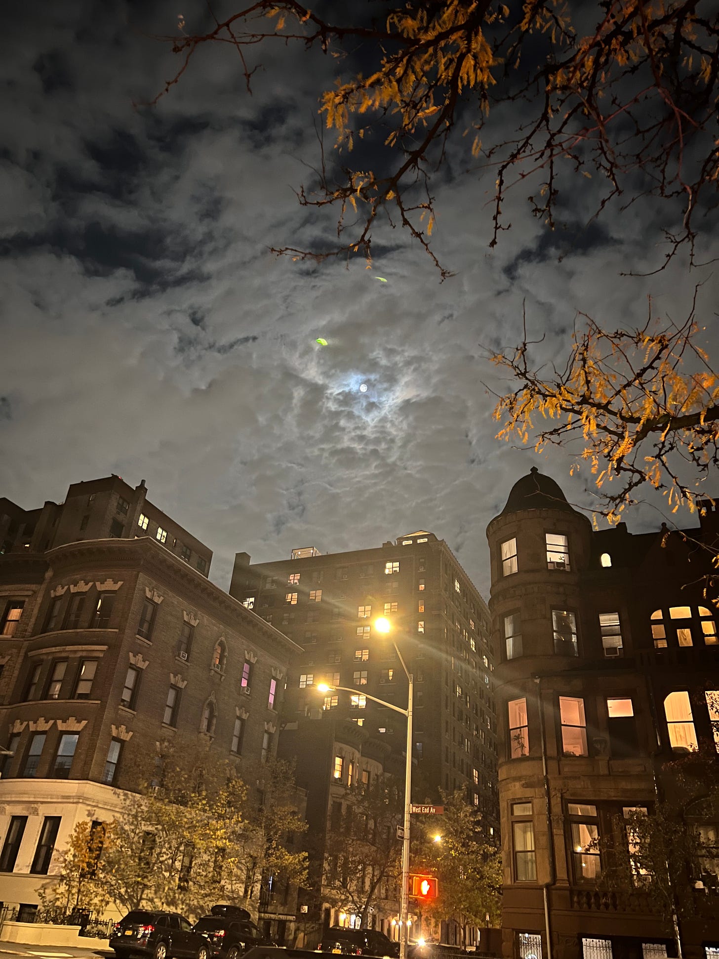 The moon peeking out from behind the clouds over a city street The moon peeking out from behind the clouds over a city street