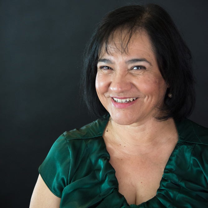 Guest Rosalba Fontanez in a green blouse against a dark backdrop