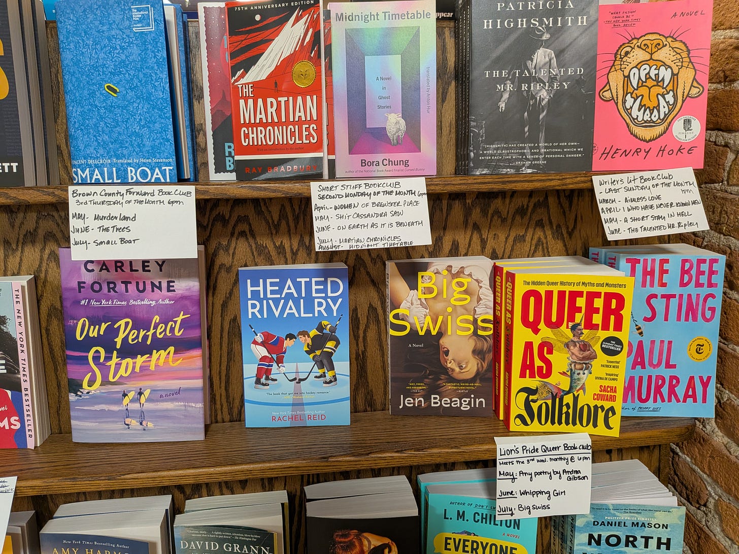 Bookshelves with different book covers facing out, accompanied by signs for upcoming book clubs Bookshelves with different book covers facing out, accompanied by signs for upcoming book clubs
