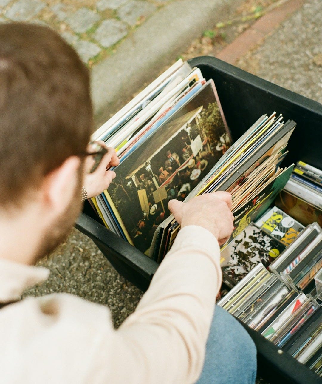 a man sitting on the ground looking at a bunch of records