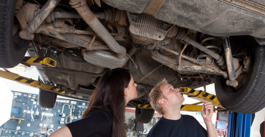 Mechanic inspecting car for rust damage