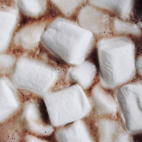 This may contain: hot chocolate with marshmallows in a white bowl