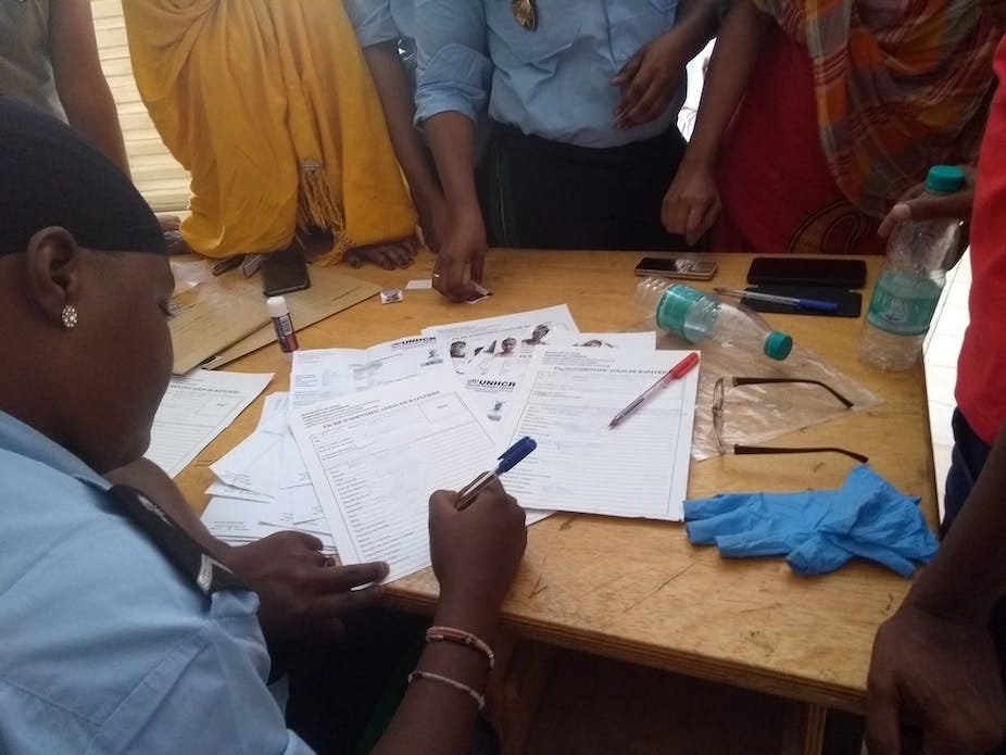 A policewoman writing on a table with people standing A policewoman writing on a table with people standing