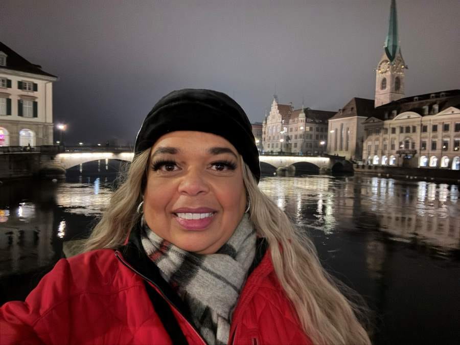 Blonde african american women, the author, standing in front of a river on bridge at night in Zurich Switzerland