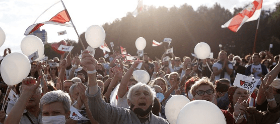 A group of people holding white balloons Description automatically generated A group of people holding white balloons Description automatically generated