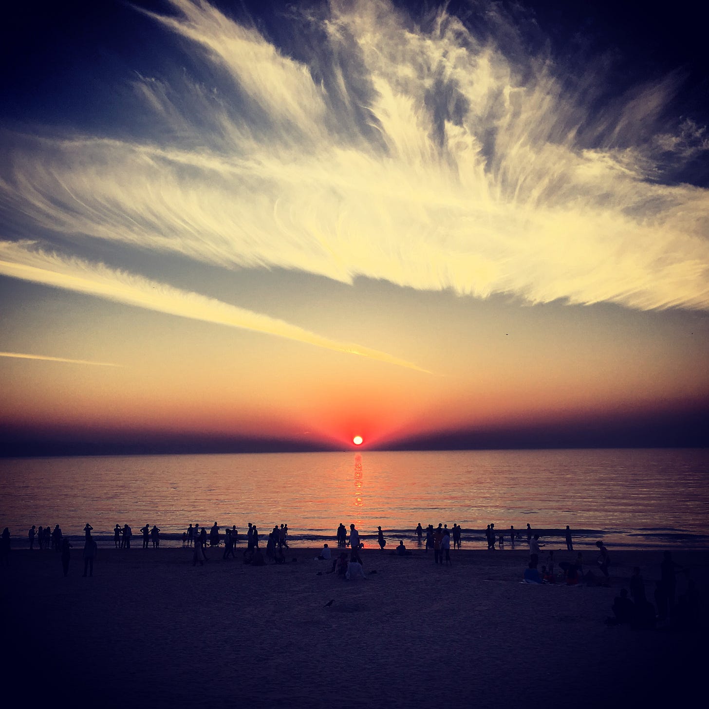 Sunset over the ocean at Juhu Beach, Mumbai; deep orange horizon with dramatic clouds.