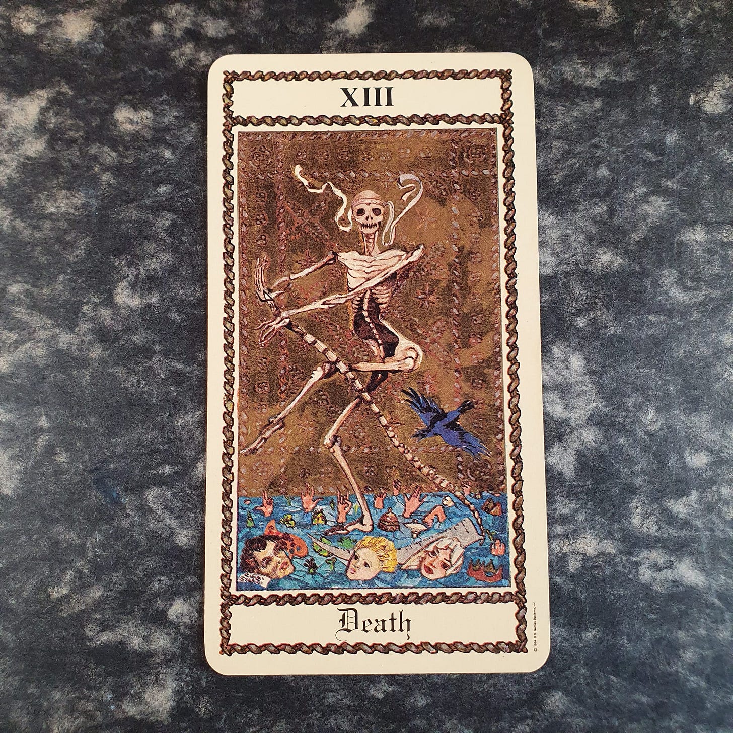 The Death tarot card, numbered XIII, showing a dancing skeleton above figures struggling in blue water. The Death tarot card, numbered XIII, showing a dancing skeleton above figures struggling in blue water.