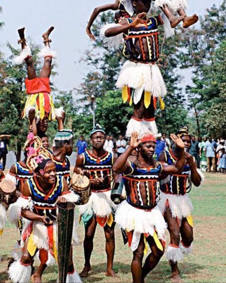 This may contain: a group of people standing on top of each other in front of some trees and grass
