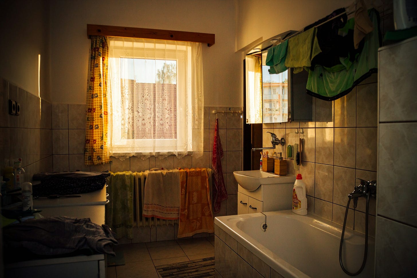 white ceramic bathtub and clothes near white ceramic sink