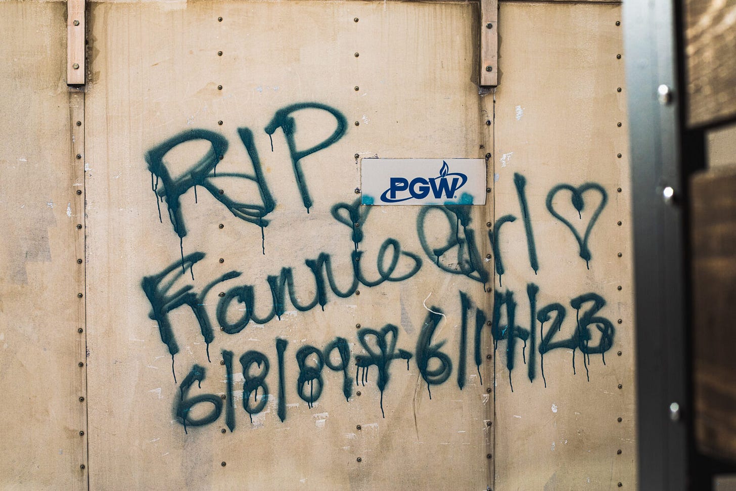 A photo of a metal wall with rough spraypaint on it reading "RIP Frannie Girl 6/8/89-6/14/23.