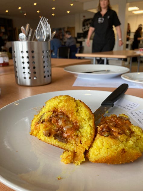 Check jacket with Great Taste Awards, jar of marmalade being examined with a computer in the background, arancini sliced in half, with cutlery and Great Taste staffer in the background.