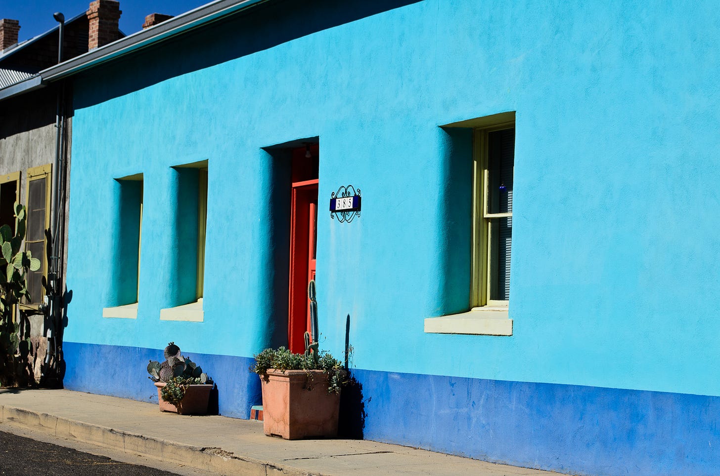 Bright teal and blue house with an orange door.