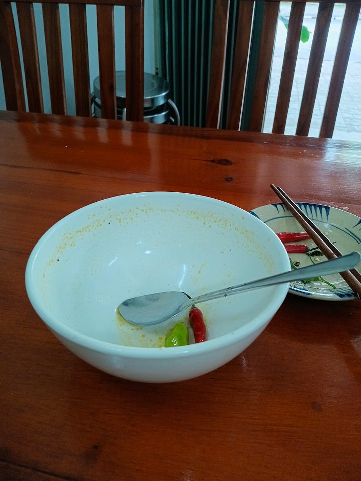 a full bowl of Bùn Cặn Nướng noodles and toppings, and an empty bowl