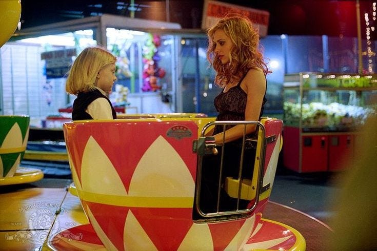 This may contain: two women are sitting in a carnival ride at the fairground, talking to each other