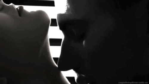 This may contain: a man and woman kissing each other in front of blinds