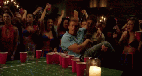 a group of people are playing beer pong with red cups on a table