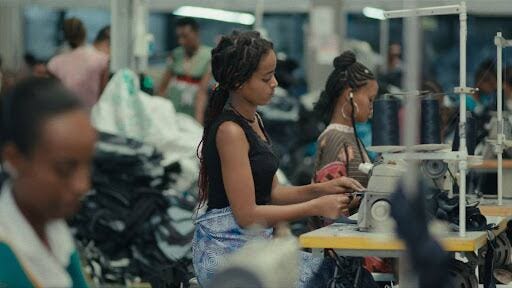 A young woman works at a sewing machine in a garment factory.