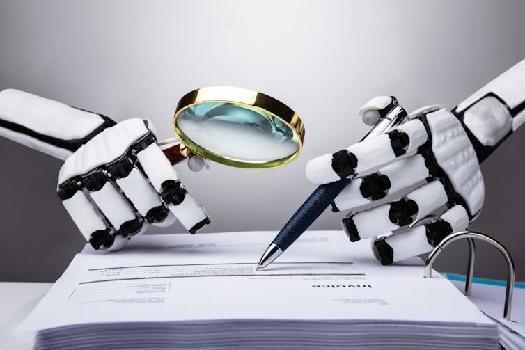 two robot hands, one holding a magnifying glass and the other a pen, over a paper document two robot hands, one holding a magnifying glass and the other a pen, over a paper document