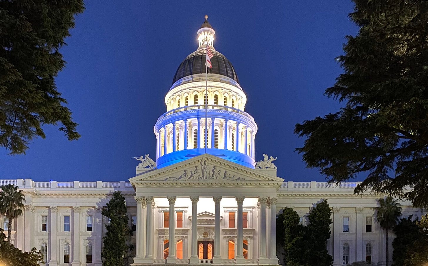 The California State Capitol at dusk with blue lights.
