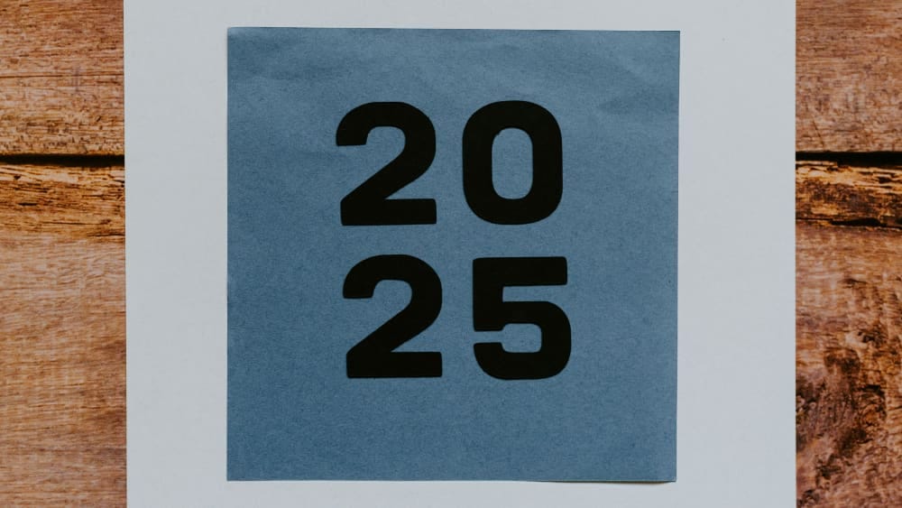 The number 2025 printed on a blue piece of paper on a wooden table