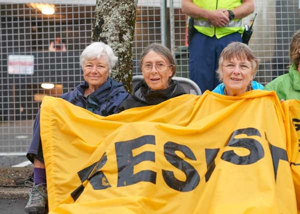 Photo of an oil blockade, featuring a banner held by Jeanette Fitzsimons, Pat Baskett, and Joanna Santa Barbara Photo of an oil blockade, featuring a banner held by Jeanette Fitzsimons, Pat Baskett, and Joanna Santa Barbara