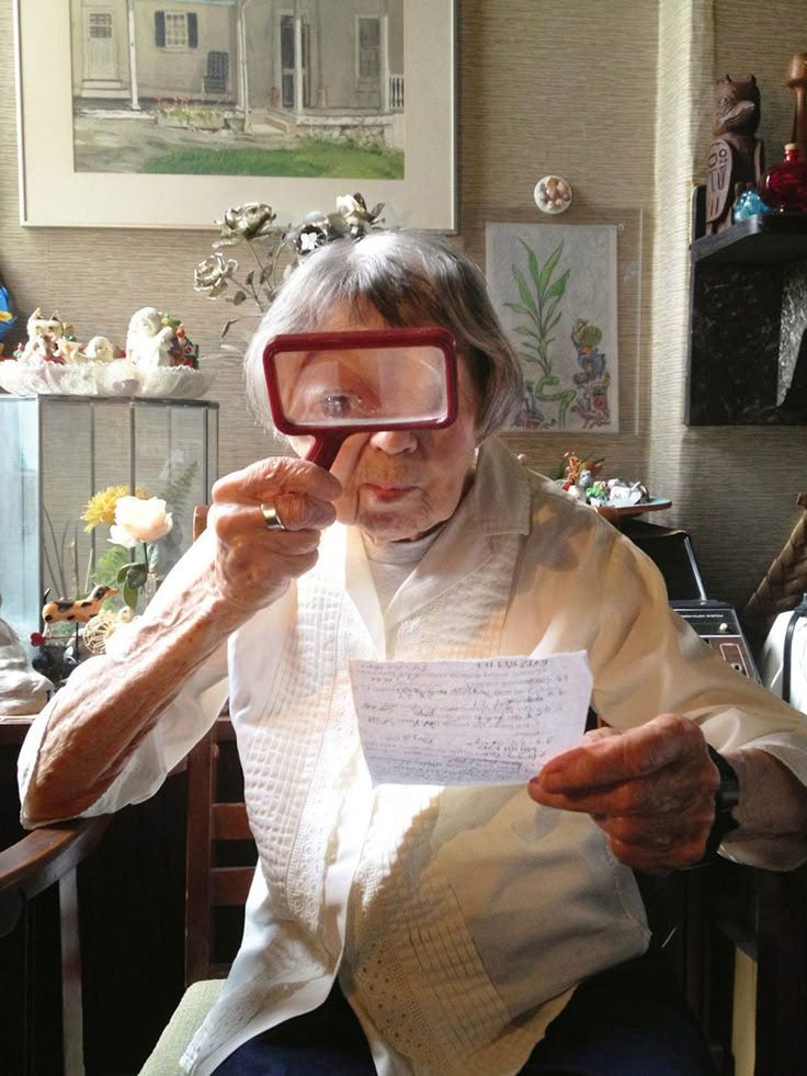 Marie Ulmer, aged 97 at the time of photograph, looking through a microscope at a letter