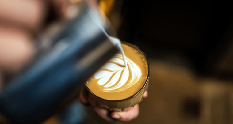 Close up of hand pouring coffee latte art