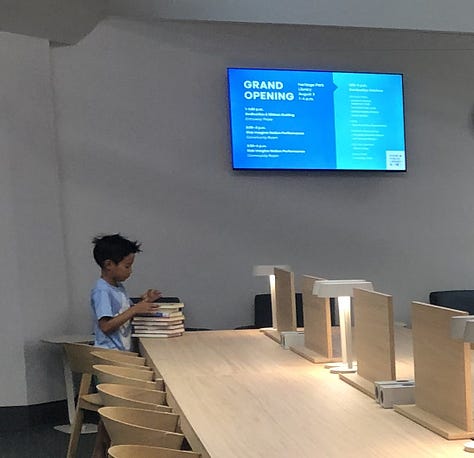 Adults and children in a public library borwworing, browsing, returning  books 