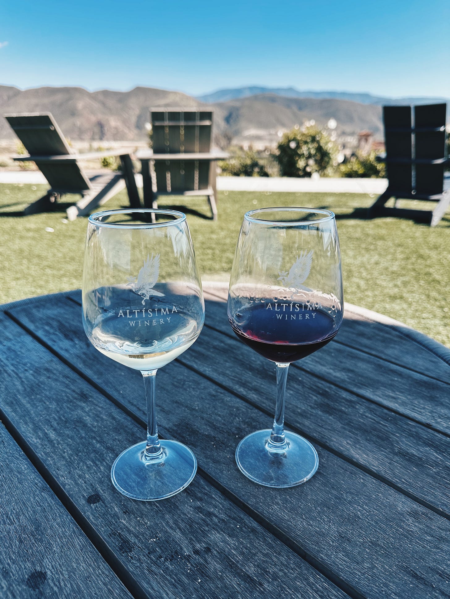 Two wine glasses with white and red wine at Altisima Winery overlooking Temecula Valley vineyards