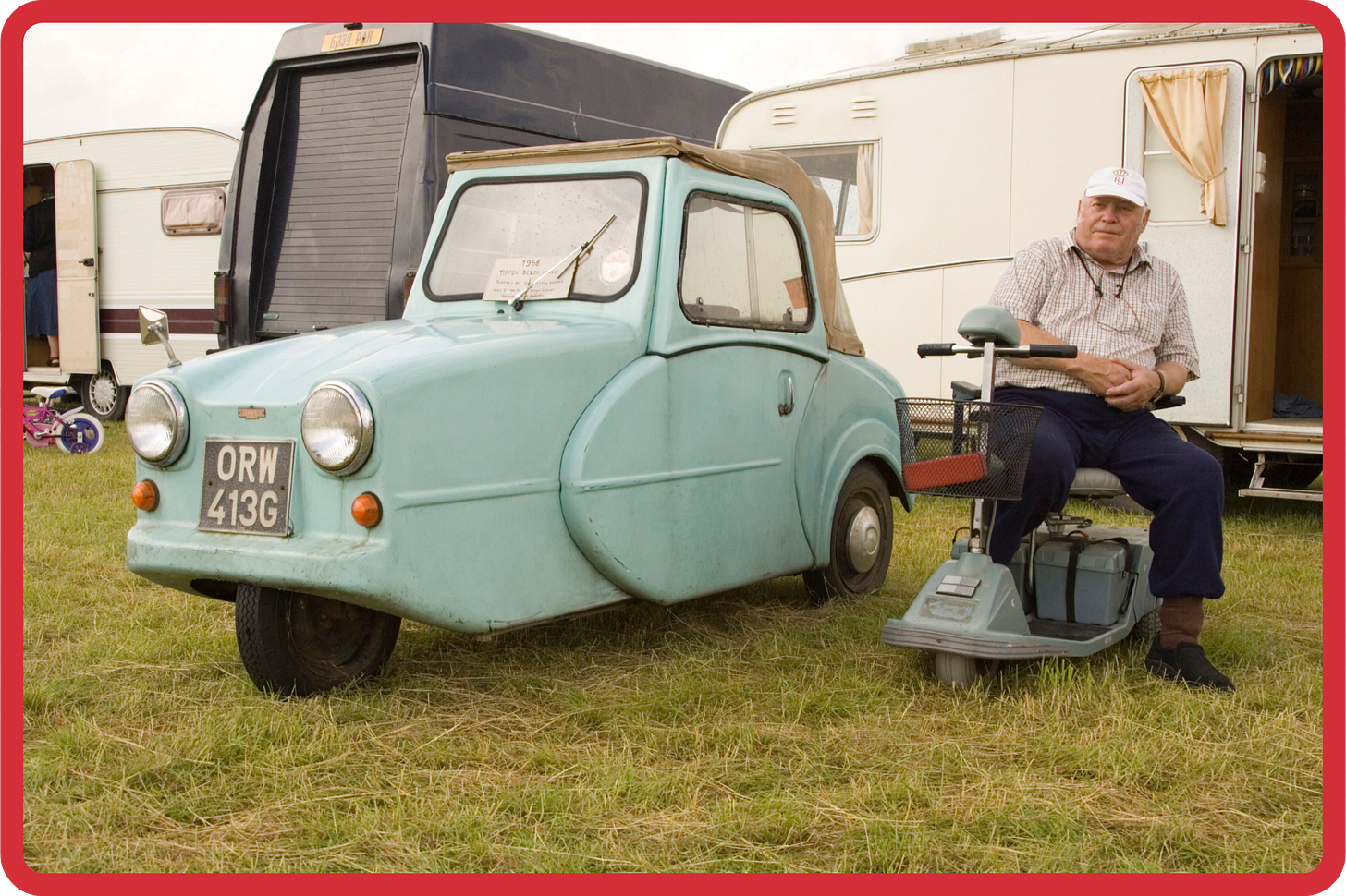 A vintage photo of a middle-aged man sat on his mobility scooter, next to a parked blue invalid carriage, inside a caravan park. The man is looking directly at the camera, with a slight smile on his face and his hands crossed on his lap. A vintage photo of a middle-aged man sat on his mobility scooter, next to a parked blue invalid carriage, inside a caravan park. The man is looking directly at the camera, with a slight smile on his face and his hands crossed on his lap.