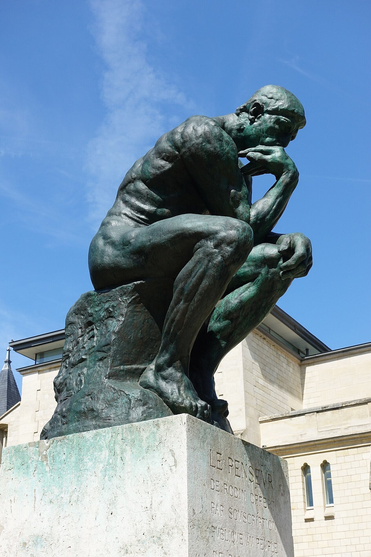 Auguste Rodin's The Thinker, a bronze seated man with his chin on his hand, in the garden of the Musée Rodin Auguste Rodin's The Thinker, a bronze seated man with his chin on his hand, in the garden of the Musée Rodin