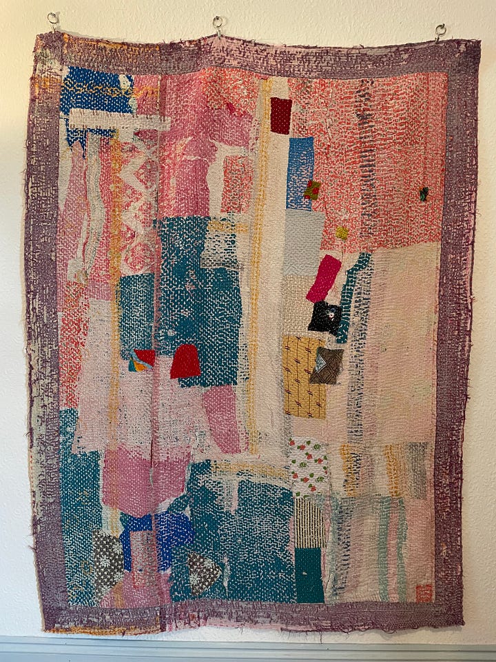 A mostly pink and blue quilt with red and yellow accents.