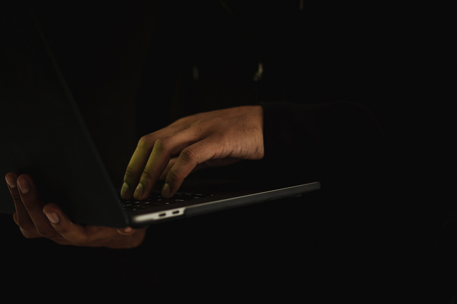 Hands emerge from black sleeves to type on a laptop Hands emerge from black sleeves to type on a laptop