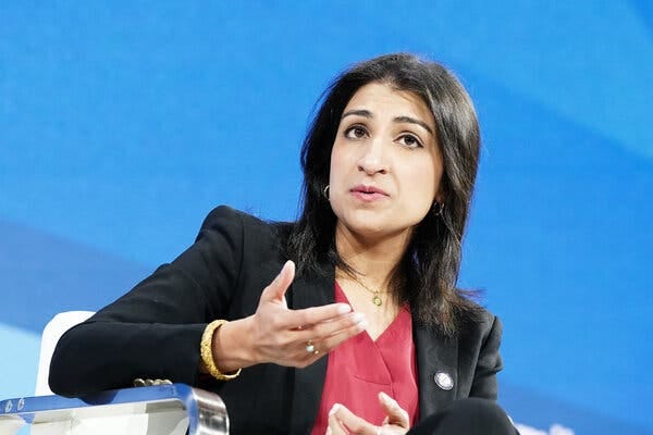 A dark-haired woman in a dark jacket gesturing.