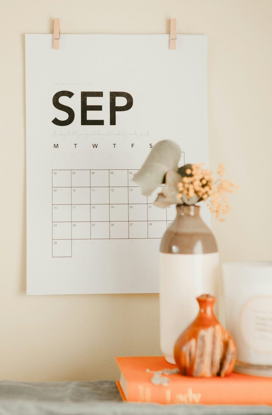 a desk with a calendar and a vase of flowers a desk with a calendar and a vase of flowers