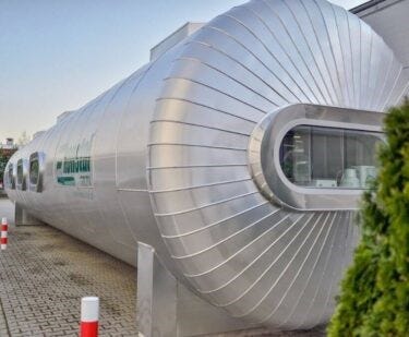 Exterior of a large, metallic, capsule-shaped hyperbaric oxygen therapy chamber with windows and polished finish.
