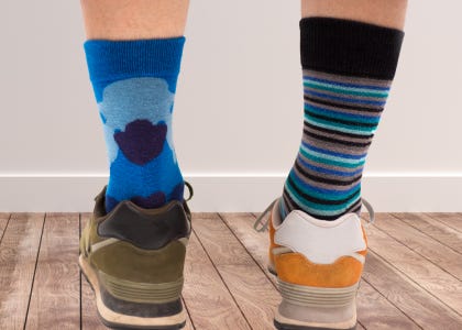 A person's legs wearing mismatched shoes and socks