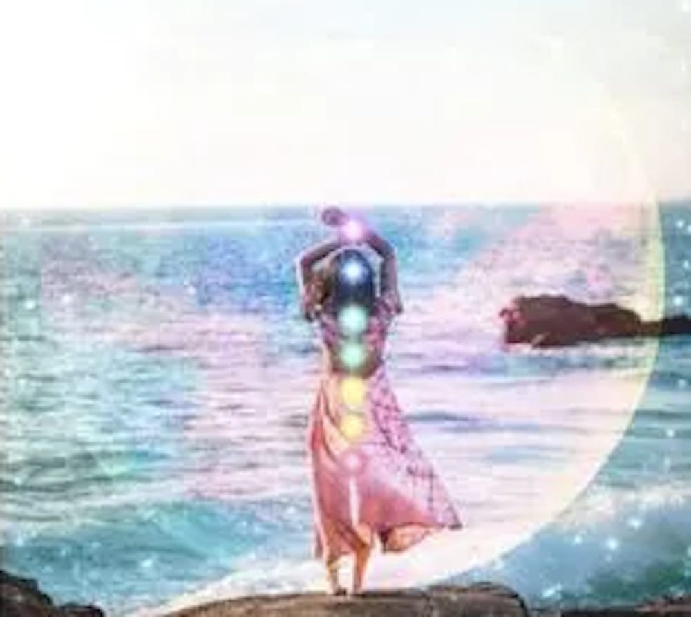 lady standing on the beach with 7 energy centers highlighted on her back