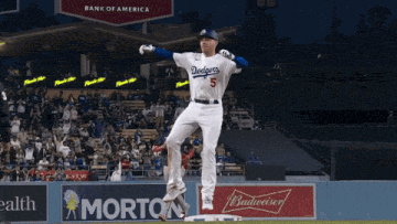 a dodgers baseball player jumps in the air while holding a bat