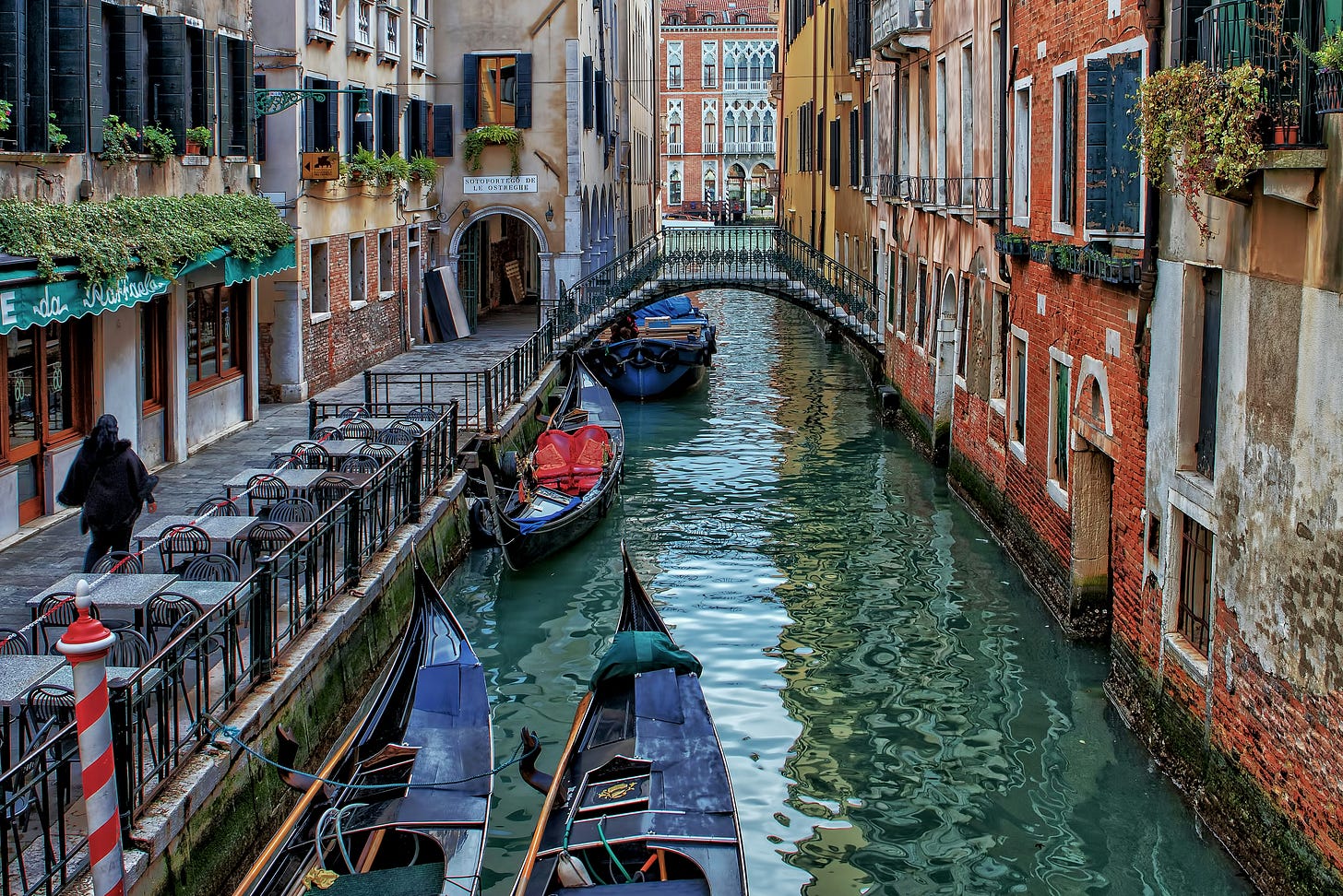 Quiet, deserted canal in Venice, one person walking on path next to canal Quiet, deserted canal in Venice, one person walking on path next to canal
