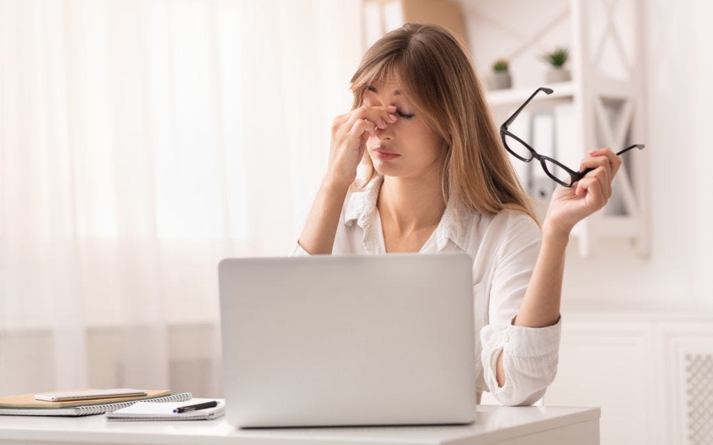 Frustrated Businesswoman Massaging Nosebridge Sitting At Workplace Frustrated Businesswoman Massaging Nosebridge Sitting At Workplace