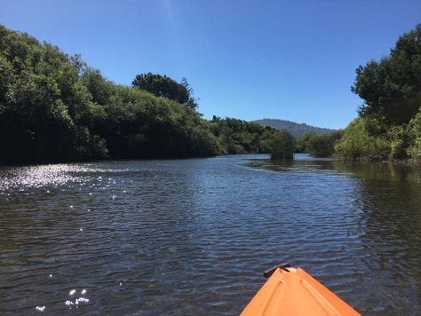 Red kayak in river, orange kayak tip, two kayers, yellow Malibu Two kayak