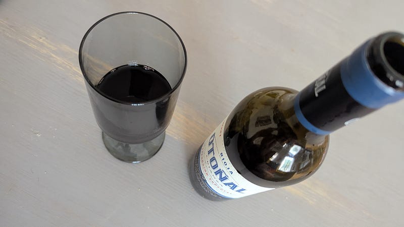 A half empty bottle of rioja next to a half empy glass of rioja on a pub table. A half empty bottle of rioja next to a half empy glass of rioja on a pub table.