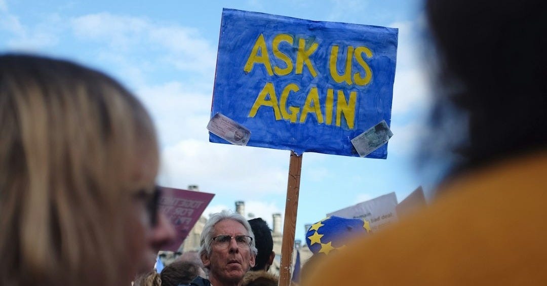 a woman holding a sign that says ask us again a woman holding a sign that says ask us again