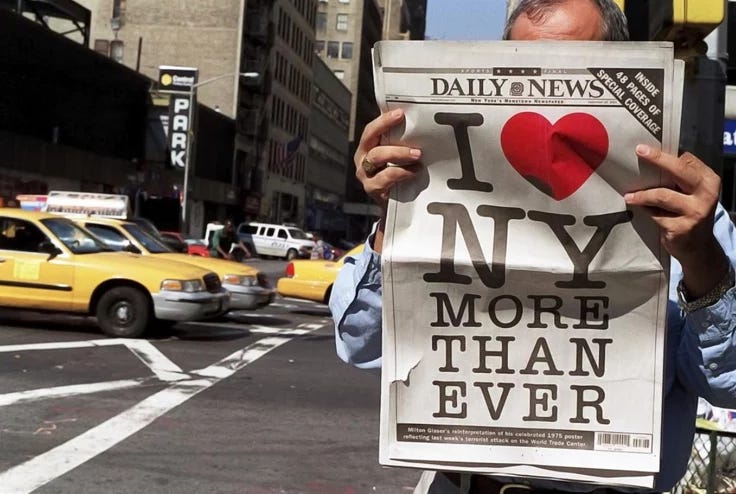 This may contain: a man holding up a newspaper that says i love new york and more than ever This may contain: a man holding up a newspaper that says i love new york and more than ever