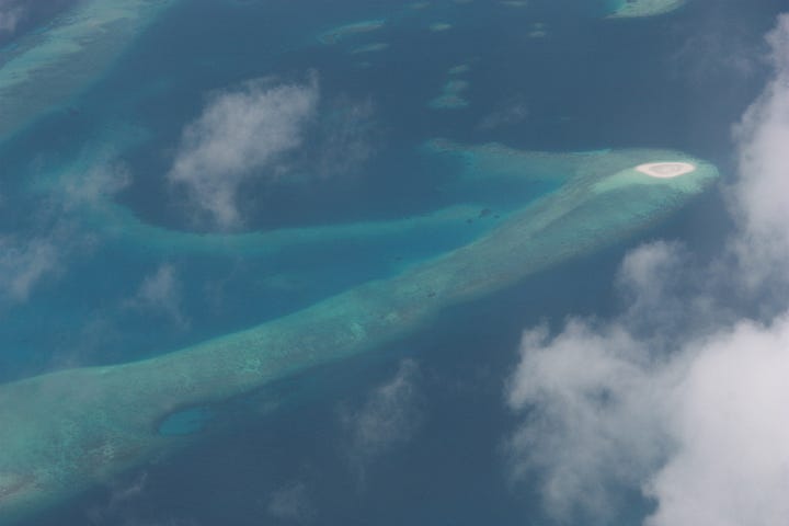 Both images show an aerial view of blue sea where the water is deep and turquoise water where it is shallow, with one image showing a small circle of white which is a sand island
